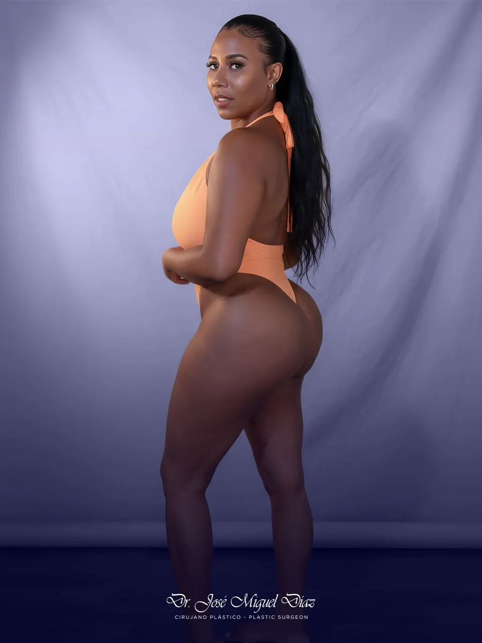 A patient of Dr. José Miguel Díaz in profile wearing swimwear, studio session on a lilac background.